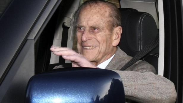 Prinz Philip sitzt angeschnallt in einem Auto und winkt.