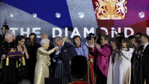 Königin Elizabeth II. und Prinz Charles bei einer Veranstaltung zum diamantenen Thronjubiläum, umgeben von Prominenten wie Elton John und Paul McCartney.