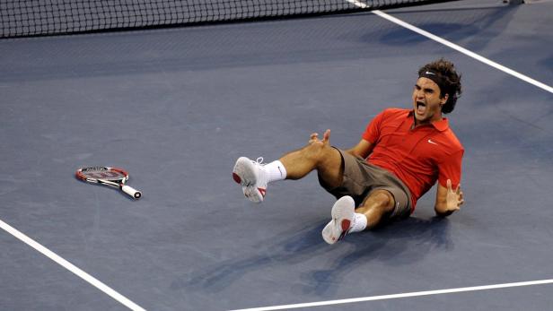 Roger Federer liegt jubelnd auf dem Tennisplatz.