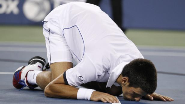 Novak Đoković kniet auf dem Tennisplatz.