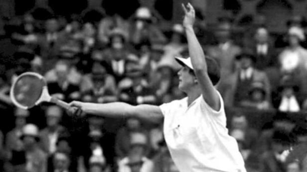 Eine Tennisspielerin beim Aufschlag vor einer Zuschauermenge.