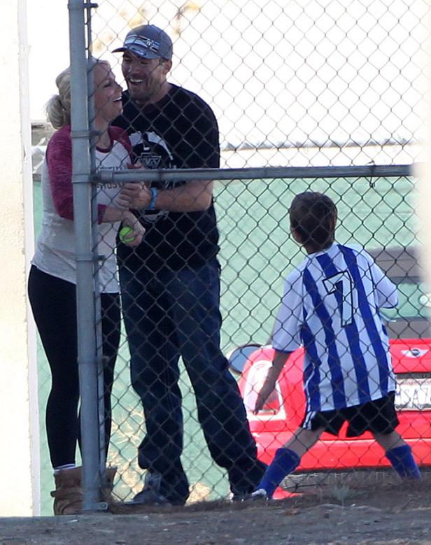 Ein Paar schaut einem Kind beim Fußballspielen zu.