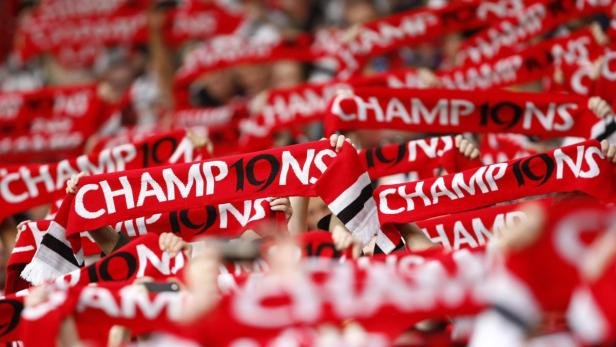 Viele Fans halten rote Schals mit der Aufschrift „Champions“ hoch.