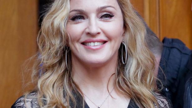 Ein Porträt von Madonna mit blonden, gewellten Haaren und silbernen Ohrringen.