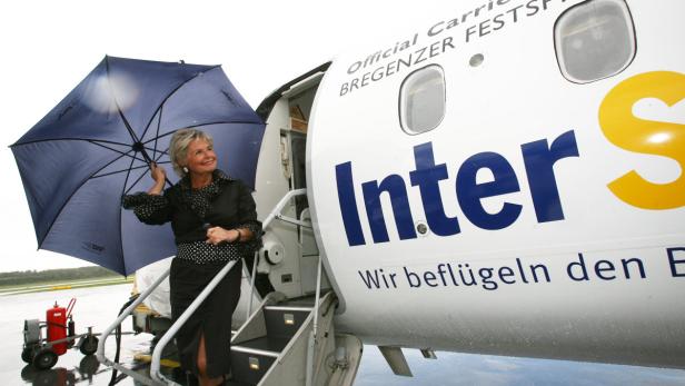 Eine Frau mit Regenschirm steigt in ein Flugzeug der InterSky ein.