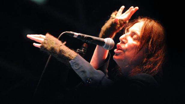 Eine Sängerin performt mit erhobenen Händen vor einem Mikrofon.