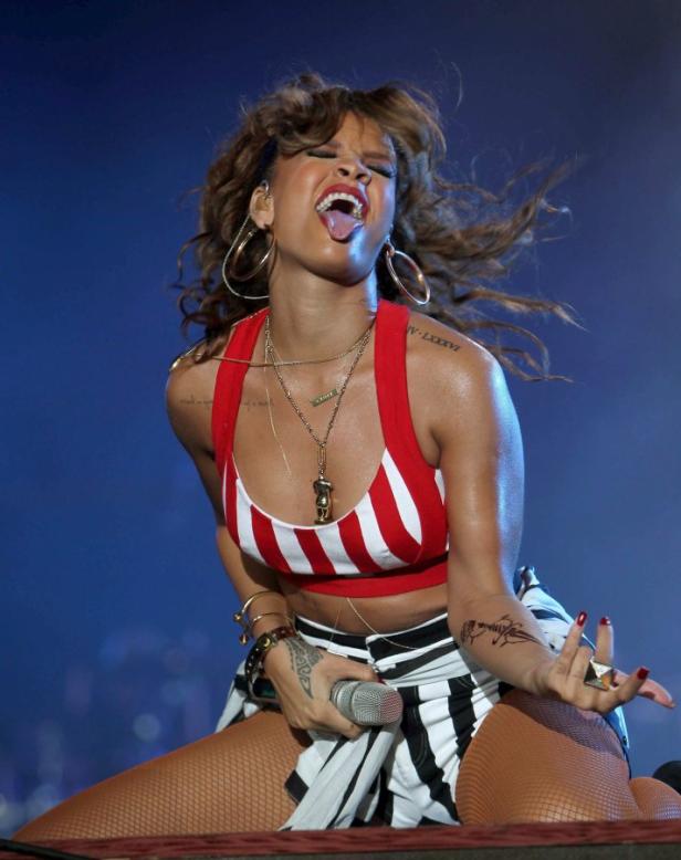 Rihanna tritt in einem rot-weiß gestreiften Top und einem schwarz-weiß gestreiften Rock auf einer Bühne auf.