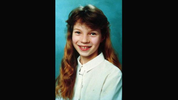 Ein Porträt der jungen Kate Moss mit langen, gewellten Haaren und einem hellen Hemd.