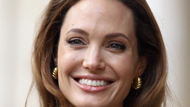 Nahaufnahme von Angelina Jolie, die lächelt und goldene Ohrringe trägt.