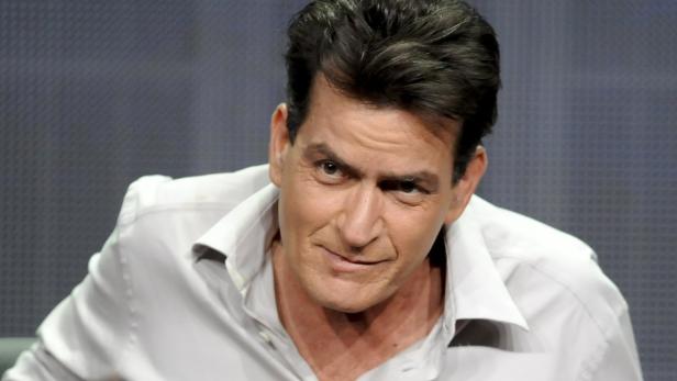 Porträt von Charlie Sheen mit einem verschmitzten Lächeln.