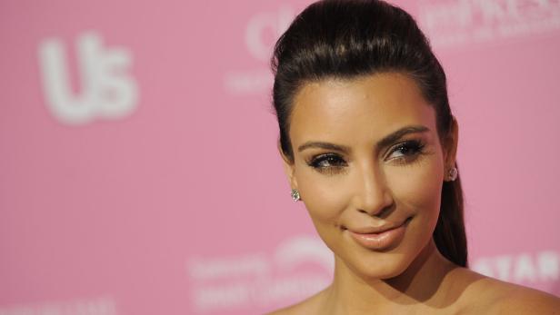 Kim Kardashian posiert vor einem rosa Hintergrund.