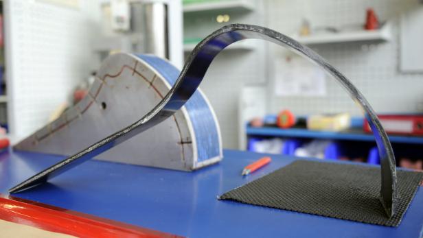 Eine gebogene Carbonfaser-Prothese auf einer Werkbank.