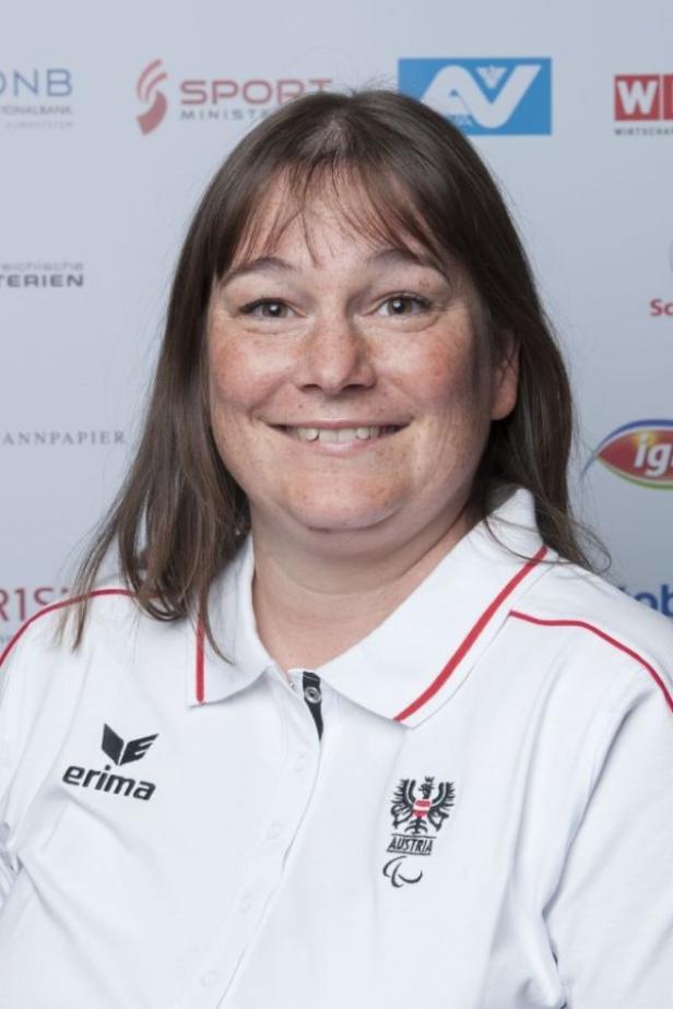 Eine Frau in einem österreichischen Sportpolo lächelt in die Kamera.