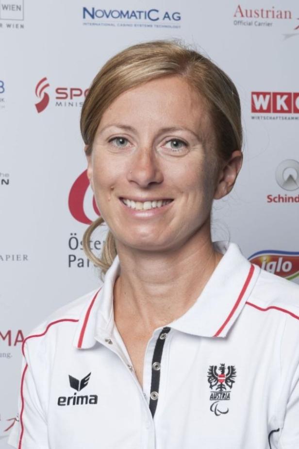 Eine lächelnde Frau in einem weißen Poloshirt mit dem österreichischen Paralympics-Logo.