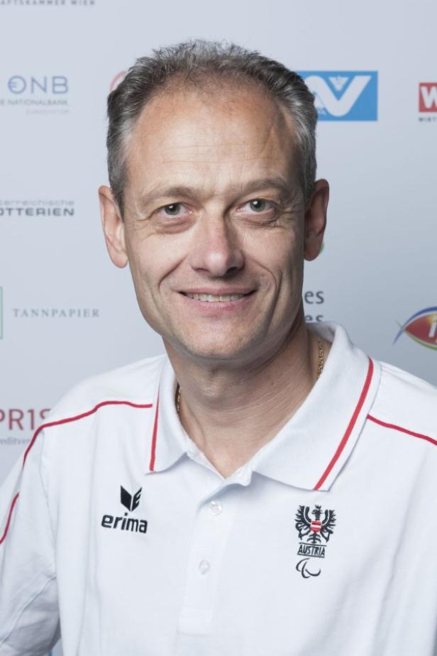 Ein Mann mit einem Poloshirt des österreichischen Paralympischen Committees lächelt in die Kamera.