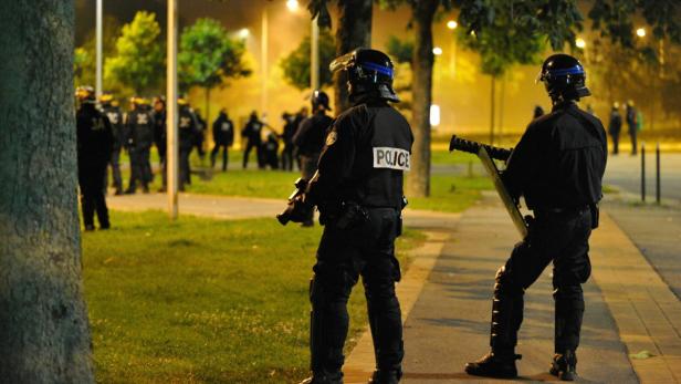 Polizisten in voller Montur stehen auf einem Bürgersteig.