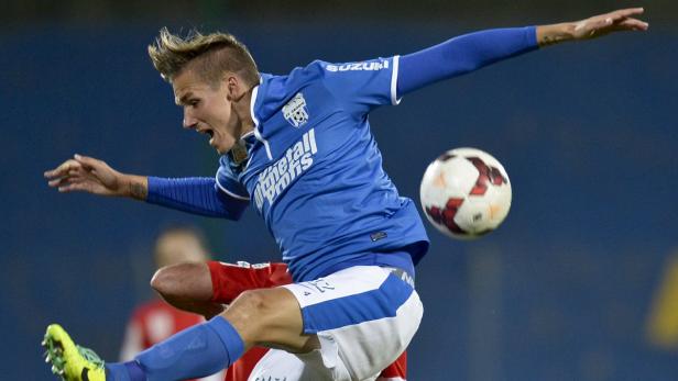 Ein Fußballspieler in blauem Trikot springt, um einen Ball zu spielen.