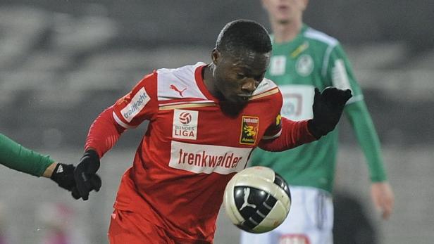 Ein Fußballspieler in einem roten Trikot mit dem Ball am Fuß.