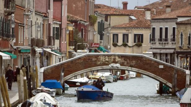 Ein Kanal in Venedig mit einer kleinen Brücke und einem Boot.