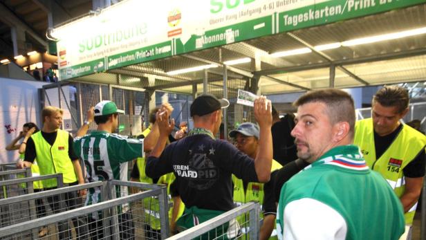 Fußballfans stehen an einem Stadioneingang unter dem Schild „Südtribüne“.
