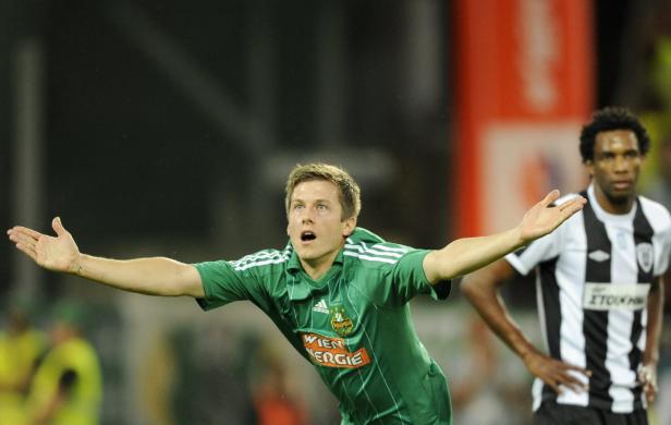 Ein Fußballspieler in Grün jubelt mit ausgestreckten Armen.