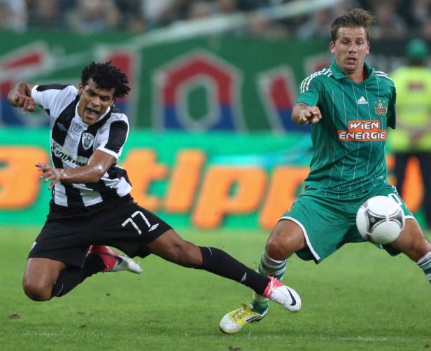 Zwei Fußballspieler kämpfen um den Ball auf dem Spielfeld.