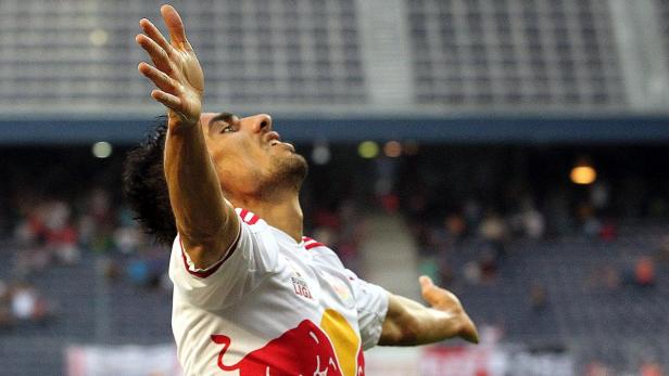 Ein Fußballspieler jubelt mit erhobenen Armen auf dem Spielfeld.