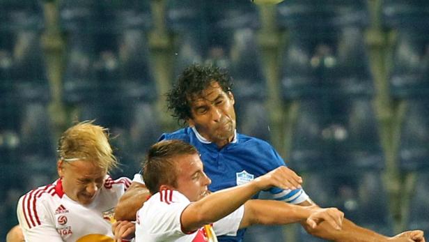 Drei Fußballspieler kämpfen um den Ball während eines Spiels.