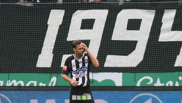 Ein Fußballspieler von Sturm Graz steht nachdenklich auf dem Spielfeld.