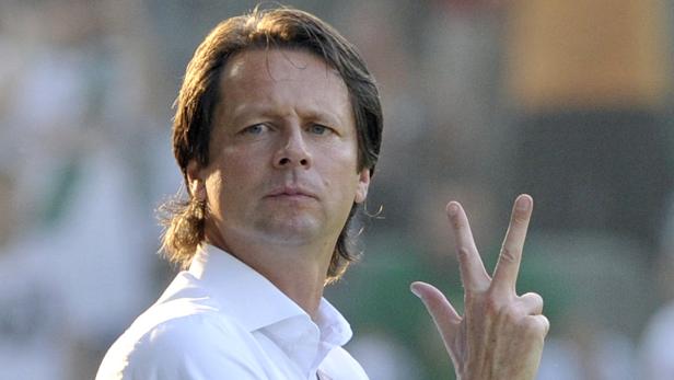 Ein Mann im weißen Hemd zeigt mit der Hand die Zahl Drei.