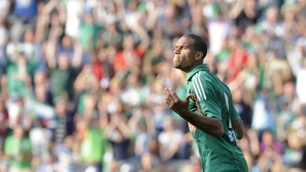 Ein Fußballspieler in Grün jubelt vor einer jubelnden Menge.