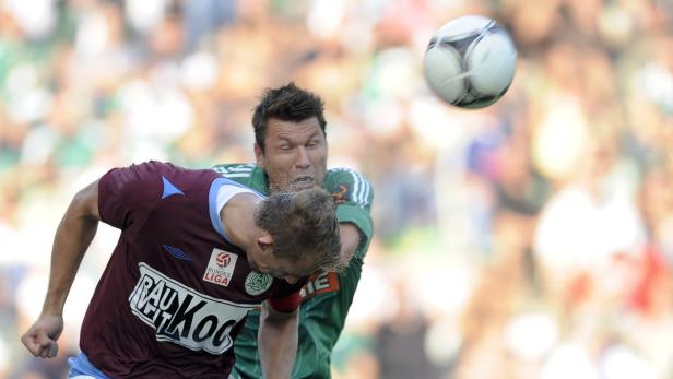 Zwei Fußballspieler kämpfen um den Ball während eines Spiels.