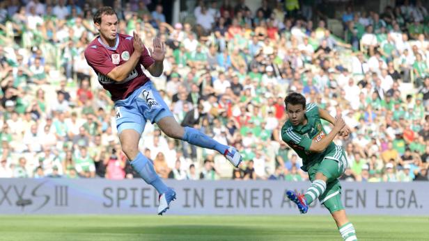 Zwei Fußballspieler in Aktion vor einer Zuschauermenge.