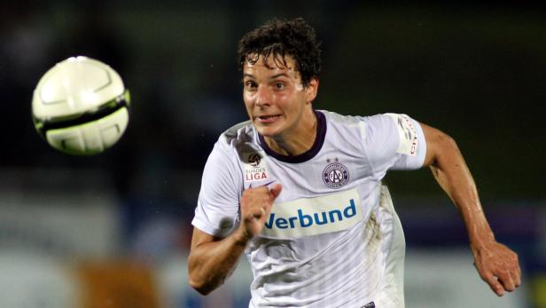 Ein Fußballspieler in einem weißen Trikot rennt auf einen Ball zu.