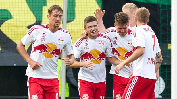 Eine Gruppe Fußballspieler in weißen und roten Trikots feiert ein Tor.