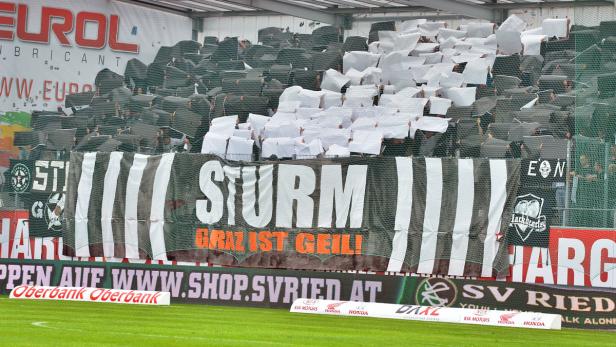 Fans von Sturm Graz zeigen während eines Spiels eine Choreografie mit Zetteln und einem Banner.