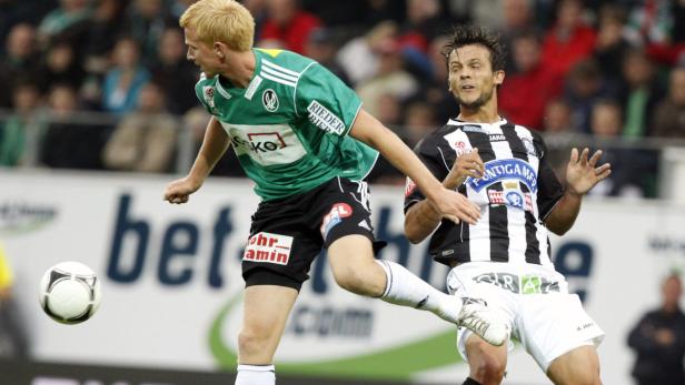 Zwei Fußballspieler kämpfen um den Ball während eines Spiels.