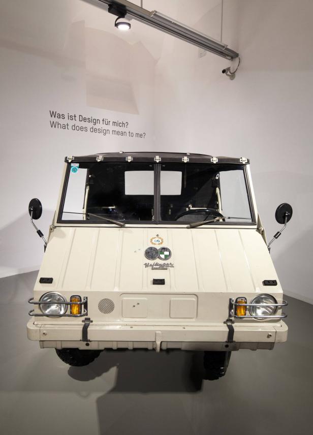 Ein beigefarbener Haflinger Geländewagen in einer Ausstellung mit der Frage „Was ist Design für mich?" an der Wand.