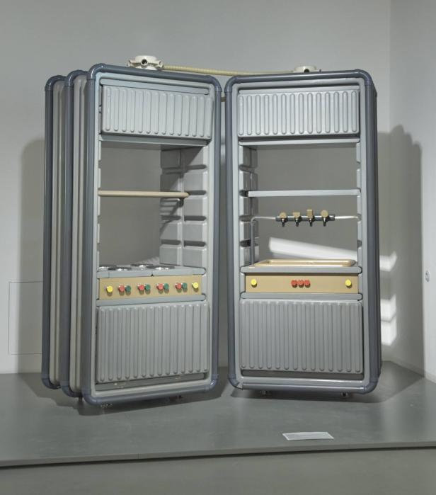 Ein geöffneter, modularer Kühlschrank mit Kochfeld und Zapfhahn steht in einem Raum.