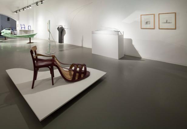 Ein Ausstellungsraum mit verschiedenen Kunstobjekten, darunter ein Stuhl mit einem Schuh darauf.
