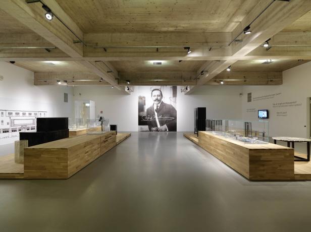 Ein Ausstellungsraum mit einem Porträt von Josef Hoffmann an der Wand.