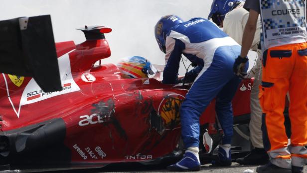 Ein beschädigter Ferrari-Rennwagen wird von Mechanikern untersucht.