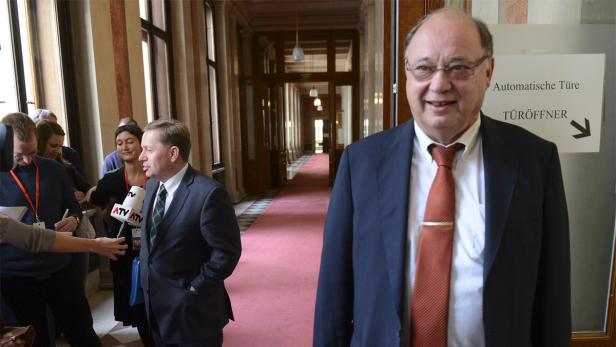 Zwei Männer in Anzügen stehen in einem Flur mit einem Schild „Automatische Türe TÜRÖFFNER“.