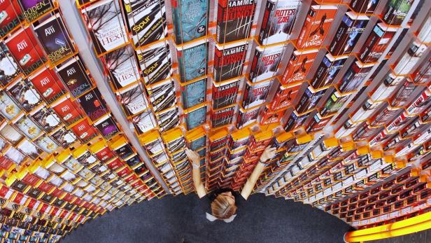 Eine Frau steht vor einem Regal voller Bücher in einem Buchladen.