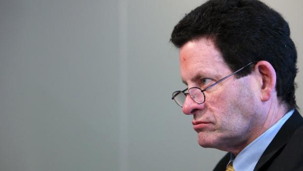 Ein Mann mit Brille und dunklen Haaren blickt nachdenklich zur Seite.