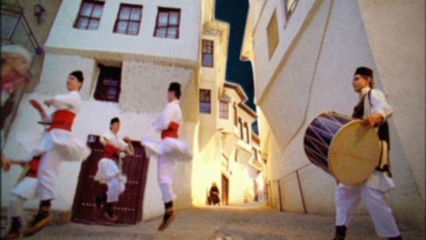 Eine Gruppe von Tänzern und ein Trommler treten in einer Gasse auf.