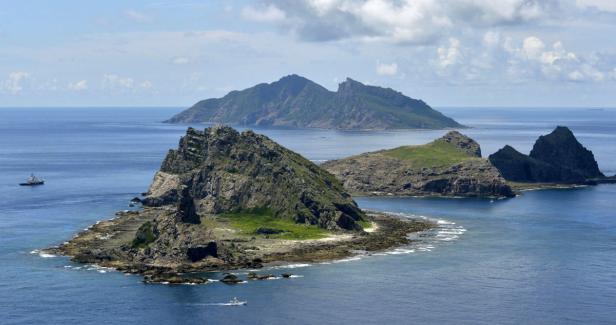 Eine Inselgruppe im Meer mit einem Schiff im Hintergrund.