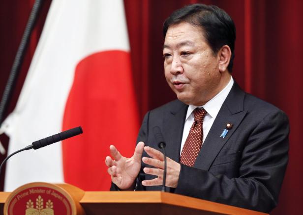 Ein japanischer Politiker spricht vor der japanischen Flagge.