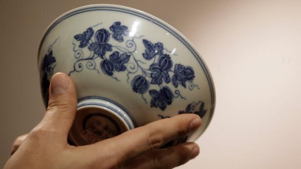 Eine Hand hält eine weiße Schale mit blauem Blumenmuster.