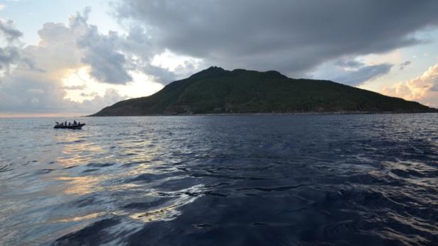 Ein kleines Boot fährt auf dem Meer in Richtung einer grünen Insel.